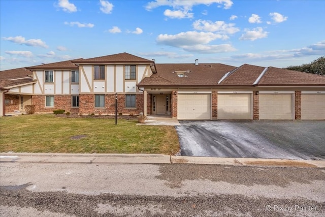 view of front of house featuring a front lawn, brick siding, and aphalt driveway