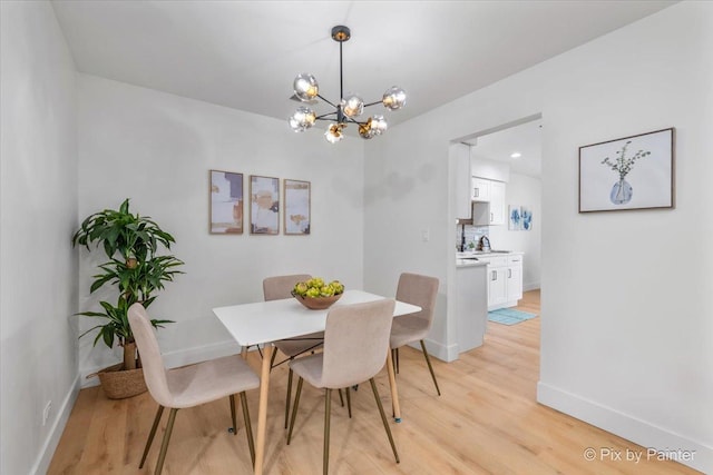 dining room with a chandelier, baseboards, and light wood finished floors