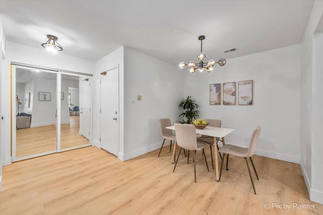 dining area with a chandelier, baseboards, visible vents, and light wood finished floors