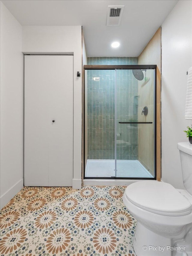 bathroom featuring toilet, a shower stall, and visible vents