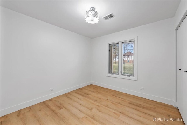 empty room featuring visible vents, baseboards, and wood finished floors