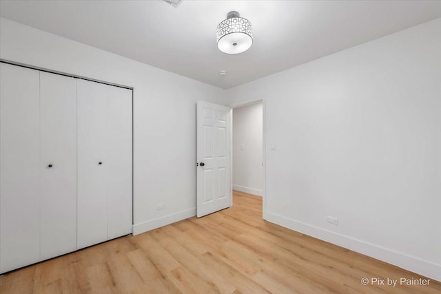 unfurnished bedroom with light wood finished floors, baseboards, and a closet