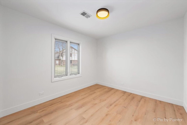 spare room featuring visible vents, light wood-style flooring, and baseboards