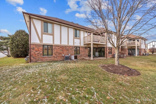 rear view of house featuring brick siding, a lawn, cooling unit, and stucco siding