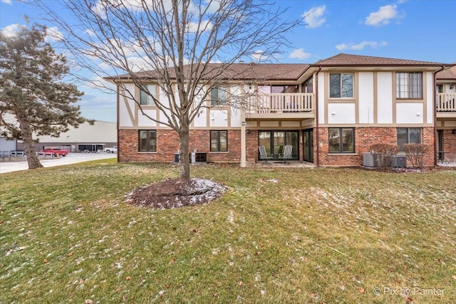 rear view of property featuring brick siding, a lawn, central AC unit, and stucco siding