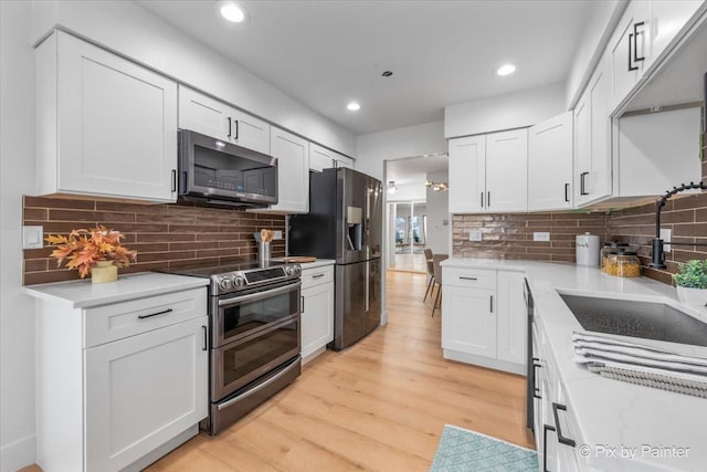 kitchen with appliances with stainless steel finishes, white cabinetry, light wood-style floors, and tasteful backsplash