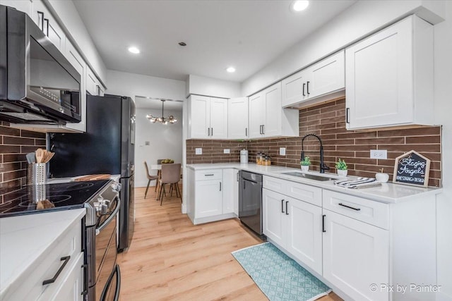 kitchen with light wood finished floors, electric stove, dishwashing machine, white cabinetry, and a sink