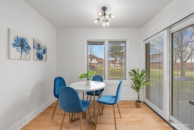 dining space with a notable chandelier, wood finished floors, and baseboards