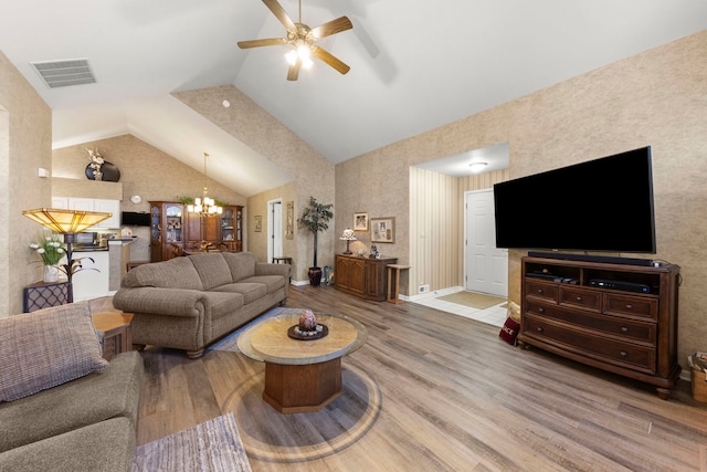 living area featuring ceiling fan with notable chandelier, visible vents, baseboards, and wood finished floors