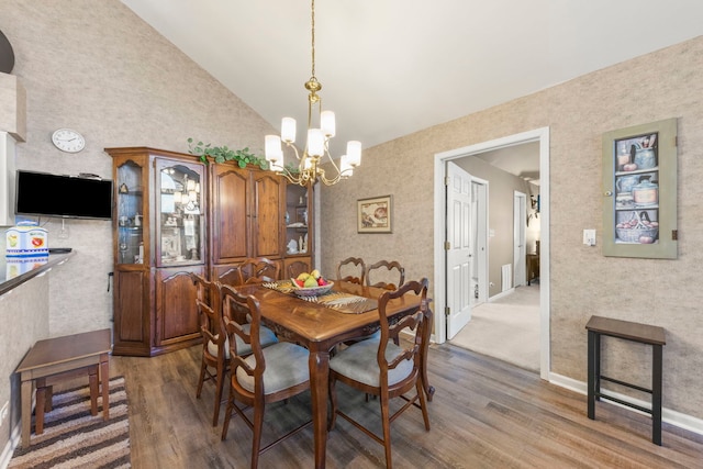 dining room featuring lofted ceiling, a notable chandelier, baseboards, and wood finished floors