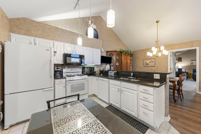 kitchen with white appliances, dark countertops, a peninsula, white cabinetry, and a sink