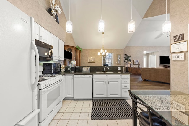 kitchen featuring white cabinetry, vaulted ceiling, a sink, white appliances, and a peninsula