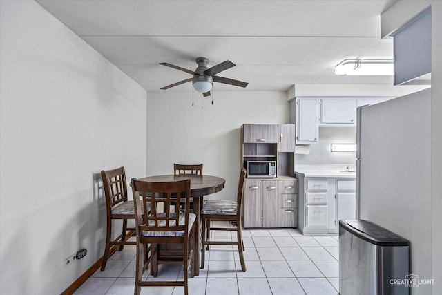 dining area featuring light tile patterned floors, a ceiling fan, and baseboards