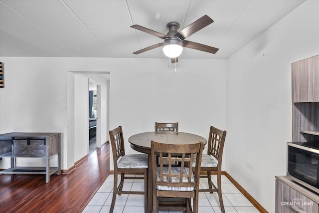 dining room featuring baseboards, light wood-type flooring, and a ceiling fan