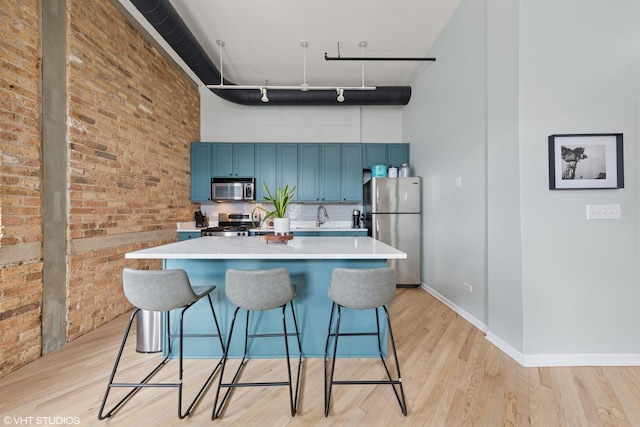 kitchen featuring blue cabinets, light wood finished floors, appliances with stainless steel finishes, and a kitchen breakfast bar