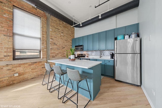 kitchen featuring stainless steel appliances, a high ceiling, and blue cabinetry