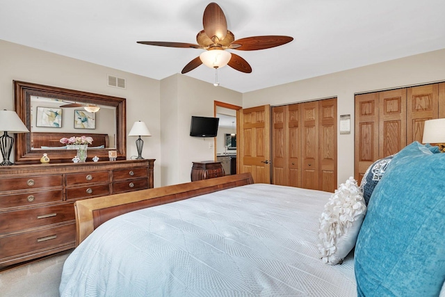 bedroom with multiple closets, carpet, visible vents, and ceiling fan