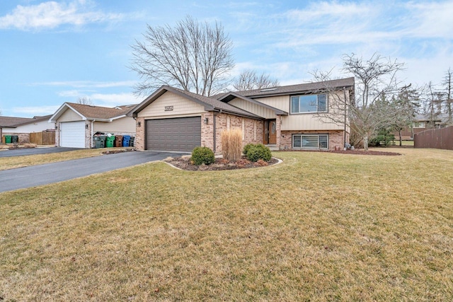 tri-level home with driveway, a garage, brick siding, fence, and a front yard