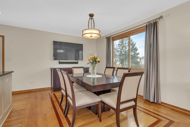 dining area featuring light wood finished floors and baseboards