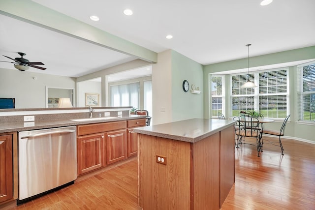 kitchen with a sink, light wood finished floors, dishwasher, and decorative light fixtures