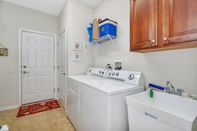 clothes washing area featuring light tile patterned floors, cabinet space, a sink, separate washer and dryer, and baseboards