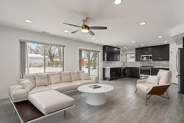 living area with light wood-style floors, recessed lighting, ceiling fan, and baseboards