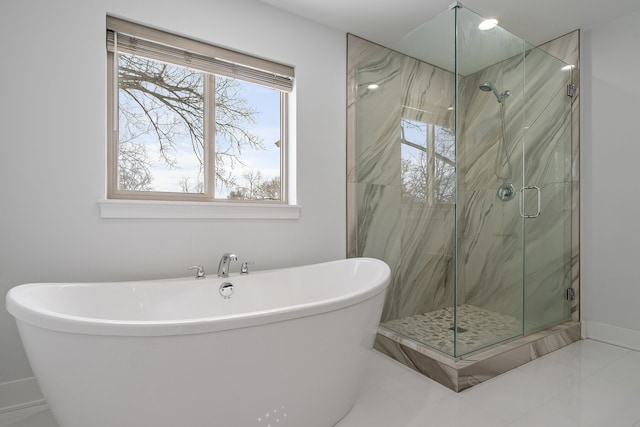 bathroom featuring a freestanding tub, a marble finish shower, and baseboards