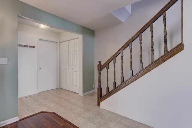 entryway with light tile patterned floors, visible vents, stairs, and baseboards