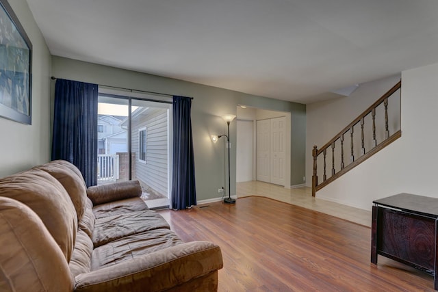 living room with stairway, baseboards, and wood finished floors