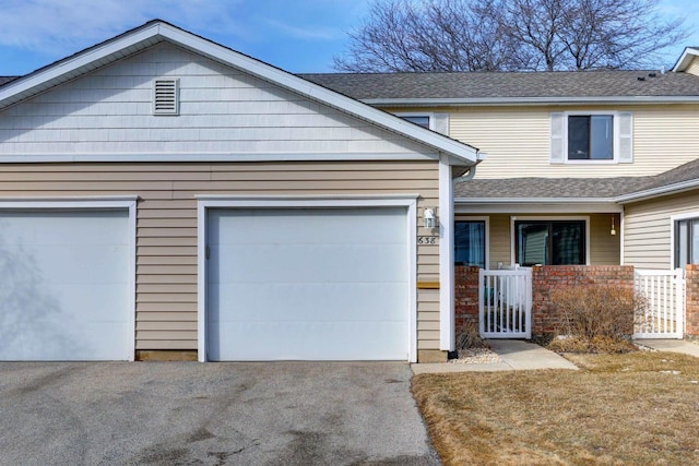 view of front of property featuring driveway, roof with shingles, and an attached garage