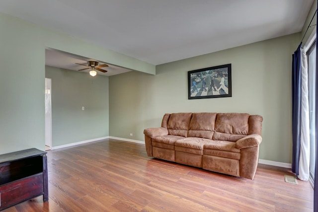 living room featuring wood finished floors, a ceiling fan, and baseboards