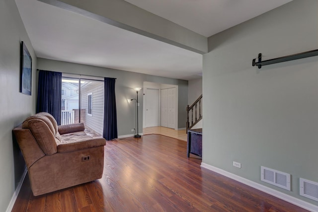 living room with visible vents, stairway, baseboards, and wood finished floors