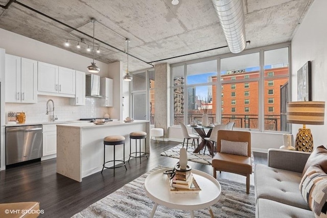 kitchen with stainless steel appliances, white cabinets, light countertops, wall chimney exhaust hood, and dark wood finished floors