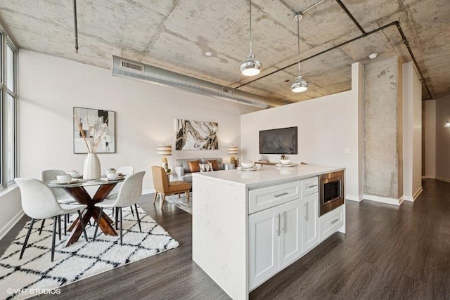 kitchen featuring dark wood-style floors, stainless steel microwave, open floor plan, light countertops, and white cabinetry