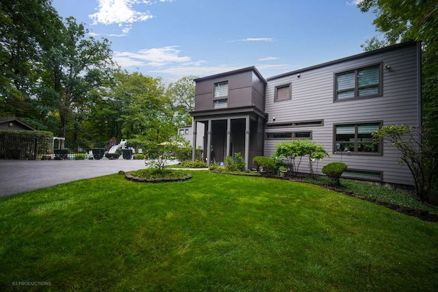 view of front of home featuring driveway, a front lawn, and fence