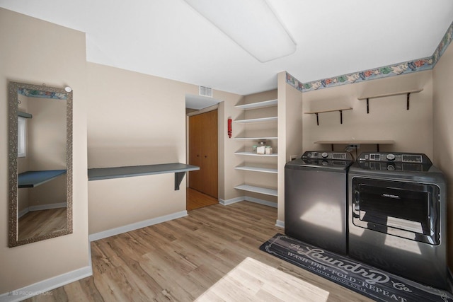 washroom with washing machine and dryer, laundry area, visible vents, and wood finished floors