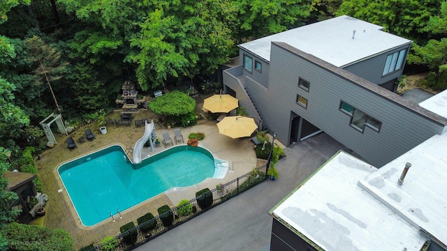 view of swimming pool featuring a patio area, a fenced in pool, fence, and a water slide