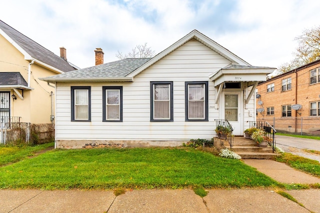 bungalow with roof with shingles, a front lawn, a chimney, and fence