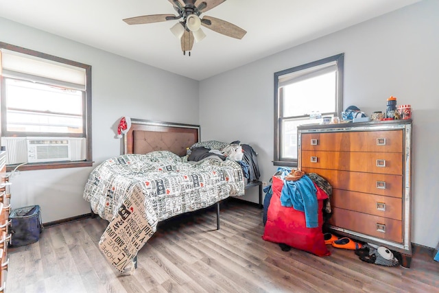 bedroom with cooling unit, wood finished floors, a ceiling fan, and baseboards