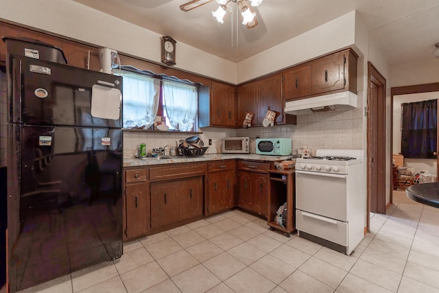 kitchen featuring gas range gas stove, tasteful backsplash, light countertops, freestanding refrigerator, and under cabinet range hood