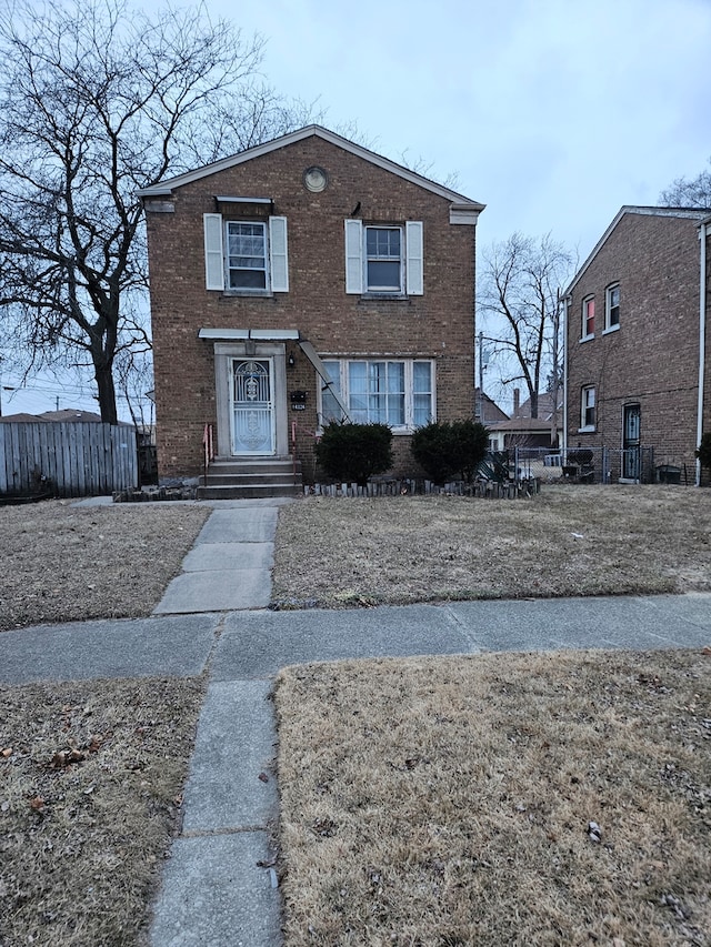 traditional home featuring brick siding and fence