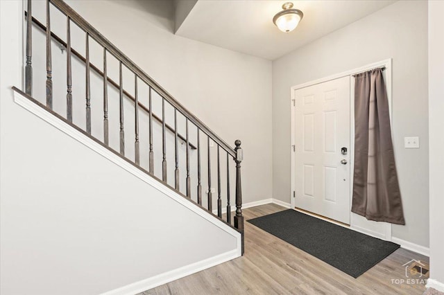 foyer entrance featuring visible vents, stairs, baseboards, and wood finished floors