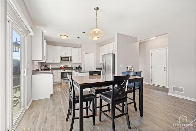 dining space with visible vents, light wood-type flooring, and baseboards