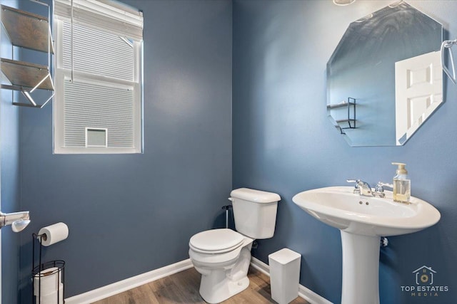 half bathroom featuring baseboards, toilet, and wood finished floors