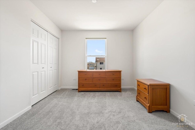 bedroom featuring baseboards, a closet, and light carpet