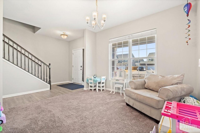 living room featuring baseboards, stairway, carpet floors, wood finished floors, and a notable chandelier