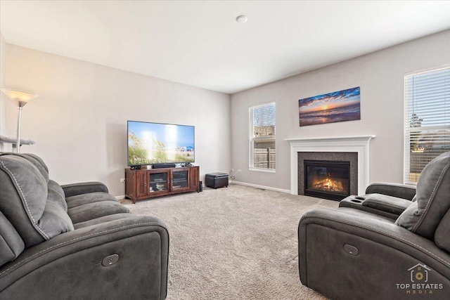 living area with a glass covered fireplace, baseboards, and carpet floors