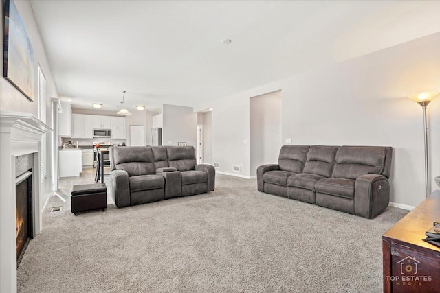 carpeted living room featuring baseboards and a lit fireplace