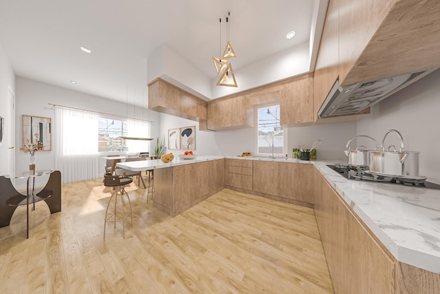 kitchen with light wood-style flooring, a peninsula, light stone countertops, modern cabinets, and decorative light fixtures