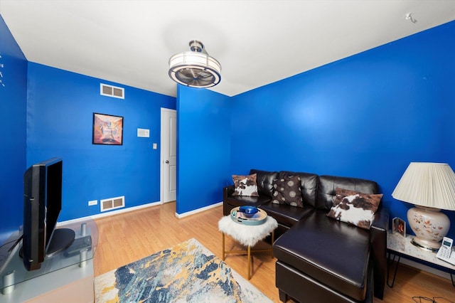 living area featuring baseboards, visible vents, and wood finished floors